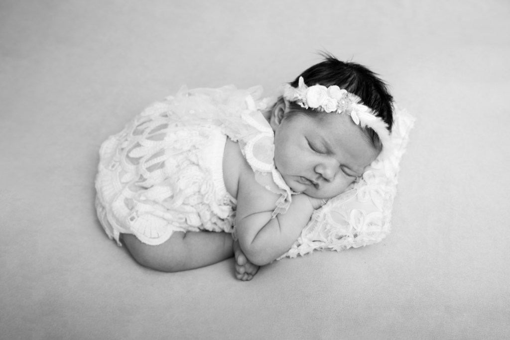 Photographie de naissance en noir et blanc d’un nouveau-né endormi, allongé dans une pose naturelle et apaisante.
